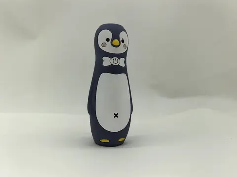 Dark navy silicone grip moulded as a penguin figure, with a printed white belly, printed eyes and yellow moulded feet.